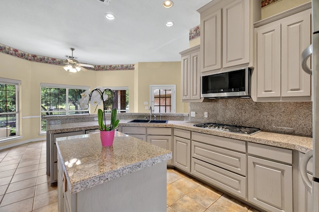 213 W Rio Rdg, Azle, TX 76020 - kitchen featuring appliances with stainless steel finishes, a sink, a peninsula, a ceiling fan, and light tile patterned floors
