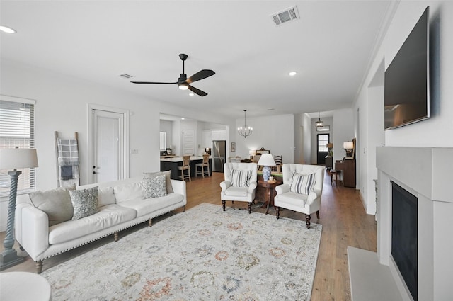 513 Fieldstone Ln, Haslet, TX 76052 - living room with ceiling fan, a fireplace with flush hearth, light wood-type flooring, recessed lighting, and a chandelier