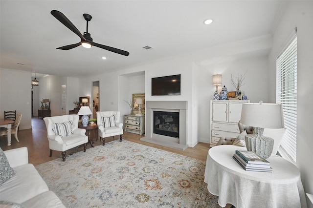 513 Fieldstone Ln, Haslet, TX 76052 - living room featuring a ceiling fan, light wood-type flooring, a glass covered fireplace, and recessed lighting