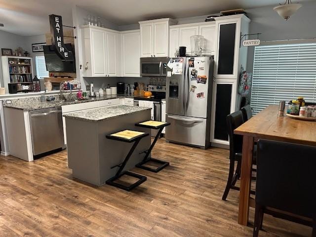 415 Magnolia, Hico, TX 76457 - kitchen with stainless steel appliances, a sink, wood finished floors, a kitchen island, and white cabinets