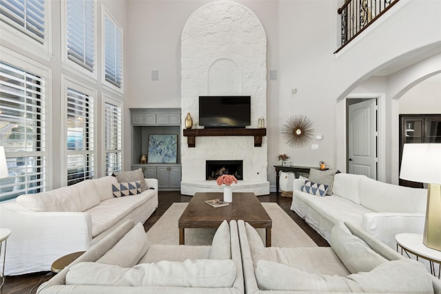 11353 Seaside Ln, Frisco, TX 75035 - living area featuring a fireplace, a towering ceiling, arched walkways, dark wood-style floors, and healthy amount of natural light