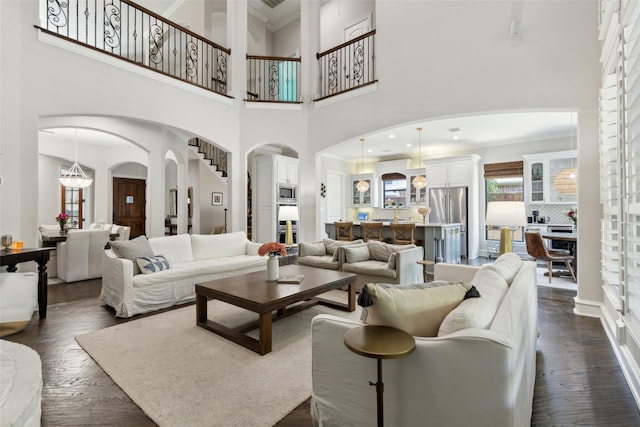 11353 Seaside Ln, Frisco, TX 75035 - living room featuring arched walkways, dark wood-style floors, a towering ceiling, and ornamental molding