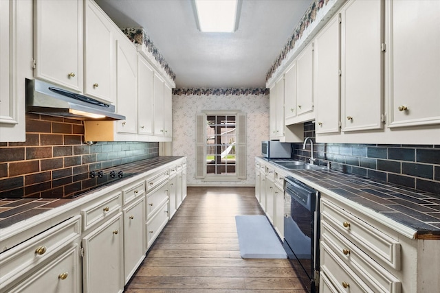 301 Peachtree St, Fairfield, TX 75840 - kitchen with under cabinet range hood, tile countertops, black appliances, white cabinets, and wallpapered walls