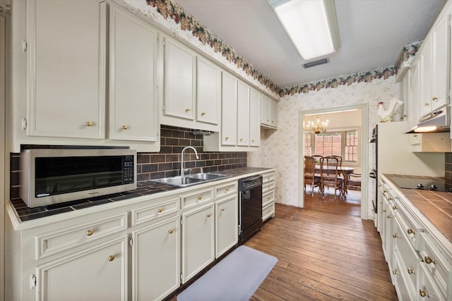 301 Peachtree St, Fairfield, TX 75840 - kitchen featuring tile counters, black appliances, wallpapered walls, a sink, and hardwood / wood-style floors