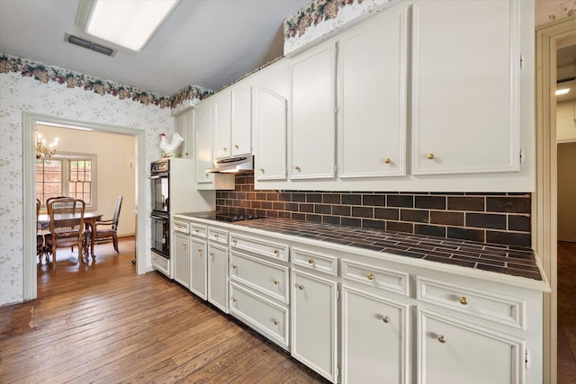 301 Peachtree St, Fairfield, TX 75840 - kitchen featuring tile countertops, black appliances, white cabinetry, wood finished floors, and under cabinet range hood
