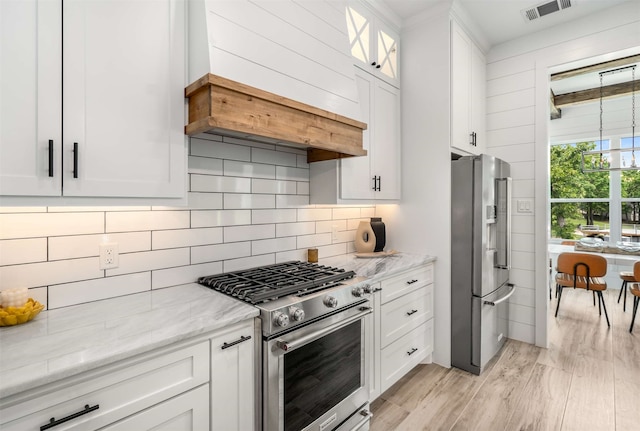 205 Oak Creek Dr, Tool, TX 75143 - kitchen with appliances with stainless steel finishes, custom exhaust hood, white cabinetry, light wood finished floors, and light stone counters