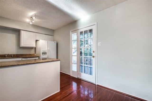 5232 Fleetwood Oaks Ave Unit 216, Dallas, TX 75235 - kitchen with white fridge with ice dispenser, a textured ceiling, white cabinetry, dark wood finished floors, and baseboards