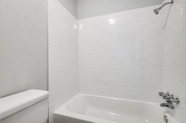 5232 Fleetwood Oaks Ave Unit 216, Dallas, TX 75235 - bathroom featuring toilet, shower / bathtub combination, and a textured wall