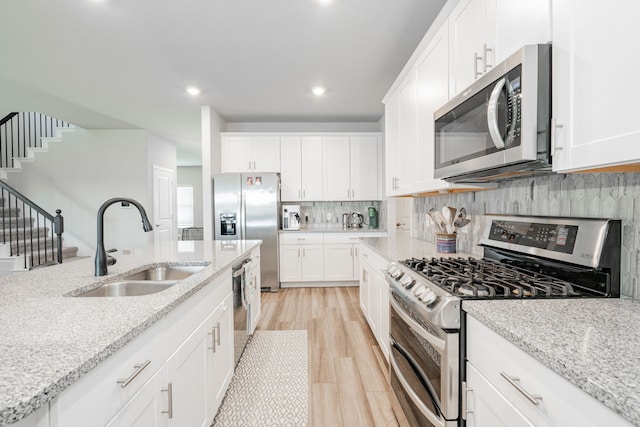 333 Mohan Dr, Royse City, TX 75189 - kitchen featuring stainless steel appliances, a sink, light wood-style floors, decorative backsplash, and white cabinetry
