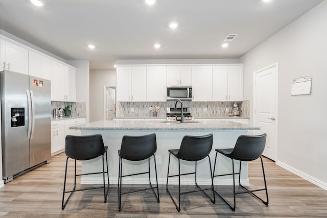 333 Mohan Dr, Royse City, TX 75189 - kitchen with stainless steel appliances, light wood finished floors, a center island with sink, tasteful backsplash, and a sink