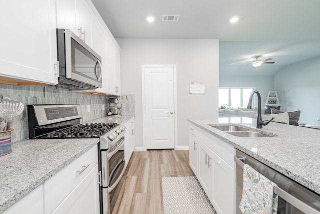 333 Mohan Dr, Royse City, TX 75189 - kitchen with stainless steel appliances, a sink, light wood-type flooring, tasteful backsplash, and white cabinetry