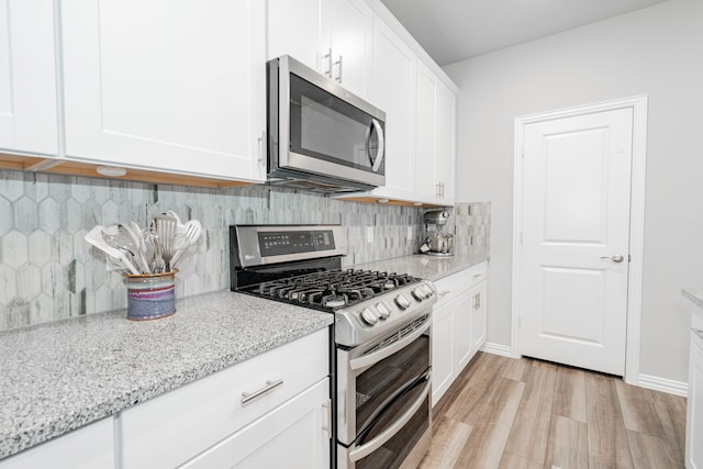 333 Mohan Dr, Royse City, TX 75189 - kitchen featuring appliances with stainless steel finishes, light wood-style floors, white cabinetry, backsplash, and light stone counters