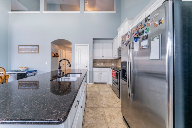 6606 Morning Dew Dr, Midlothian, TX 76065 - kitchen with appliances with stainless steel finishes, a sink, arched walkways, a high ceiling, and light tile patterned floors