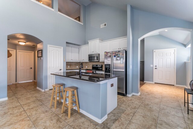 6606 Morning Dew Dr, Midlothian, TX 76065 - kitchen featuring stainless steel appliances, arched walkways, tasteful backsplash, white cabinetry, and a sink