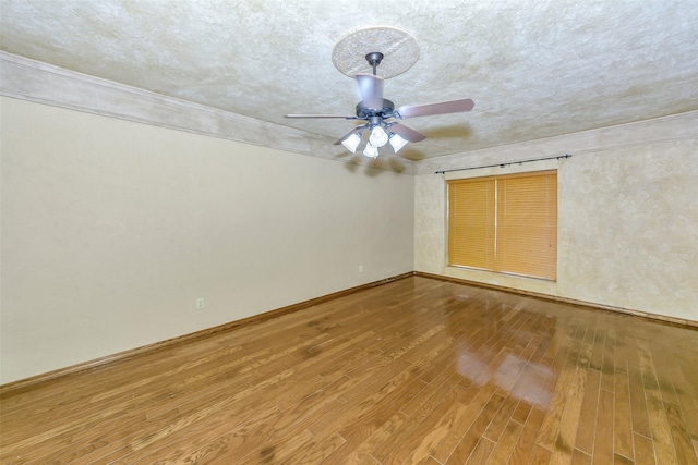 empty room with wood finished floors, a ceiling fan, crown molding, baseboards, and a textured ceiling