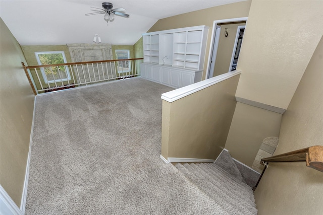 staircase featuring a ceiling fan, carpet flooring, lofted ceiling, and baseboards