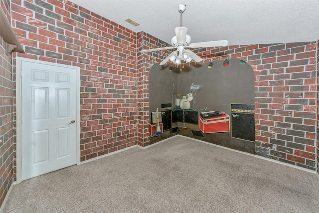 unfurnished dining area with carpet floors, brick wall, a ceiling fan, and a textured ceiling