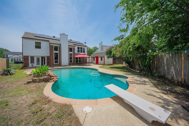 view of swimming pool with a fenced backyard, a shed, a diving board, an outdoor structure, and a patio area