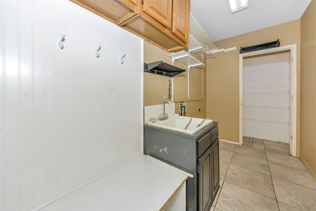 clothes washing area with a sink, light tile patterned flooring, and baseboards