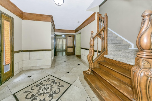foyer entrance with ornamental molding, stairs, light tile patterned flooring, and inlaid floor details