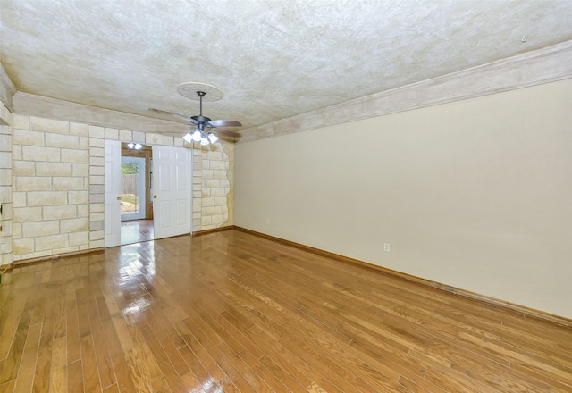 spare room featuring wood-type flooring, ornamental molding, ceiling fan, and baseboards