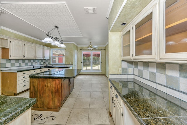 kitchen featuring a sink, decorative backsplash, ceiling fan, glass insert cabinets, and ornamental molding