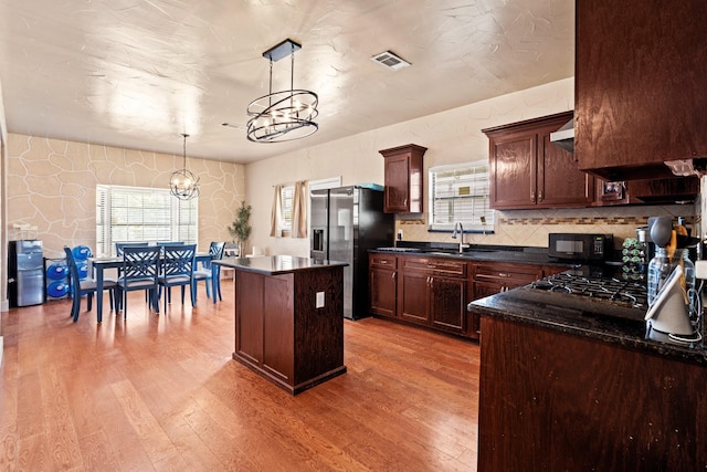 522 Helena St, Dallas, TX 75217 - kitchen with a chandelier, dark countertops, wood finished floors, and a kitchen island