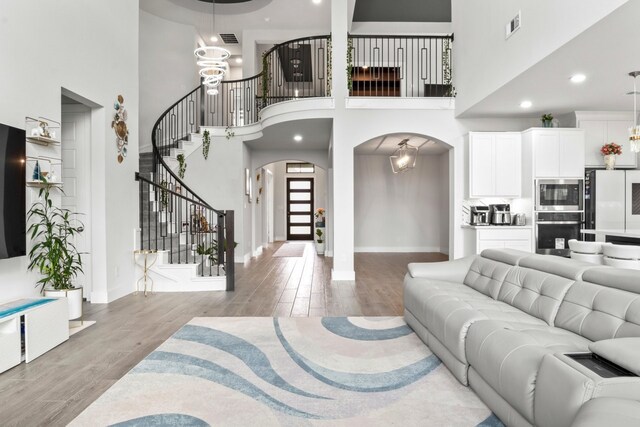 2229 Boboli Ct, Celina, TX 75009 - living room featuring arched walkways, stairway, a high ceiling, wood finished floors, and baseboards