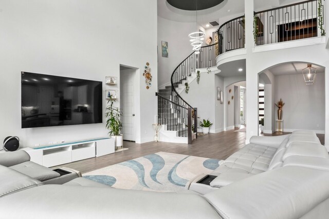 2229 Boboli Ct, Celina, TX 75009 - living room featuring wood finished floors, arched walkways, a towering ceiling, stairway, and baseboards