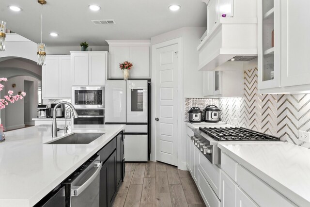 2229 Boboli Ct, Celina, TX 75009 - kitchen with a sink, appliances with stainless steel finishes, arched walkways, light countertops, and white cabinetry
