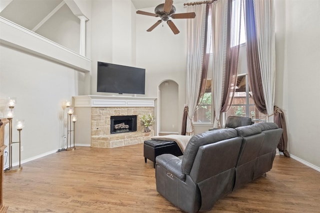 2671 Marshall Dr, Frisco, TX 75033 - living area with a ceiling fan, a towering ceiling, wood finished floors, a fireplace, and arched walkways