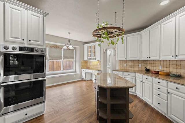 2671 Marshall Dr, Frisco, TX 75033 - kitchen featuring double oven, white cabinets, tasteful backsplash, dark wood-style flooring, and light stone countertops