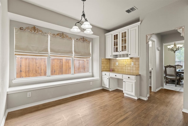 2671 Marshall Dr, Frisco, TX 75033 - kitchen with a chandelier, white cabinetry, wood finished floors, backsplash, and glass insert cabinets