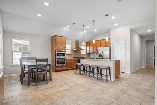 6620 Roaring Crk, Denton, TX 76226 - kitchen with stainless steel appliances, wall chimney exhaust hood, backsplash, a center island with sink, and a breakfast bar