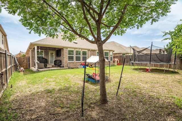 6620 Roaring Crk, Denton, TX 76226 - rear view of house featuring a trampoline, brick siding, a shingled roof, and a patio area