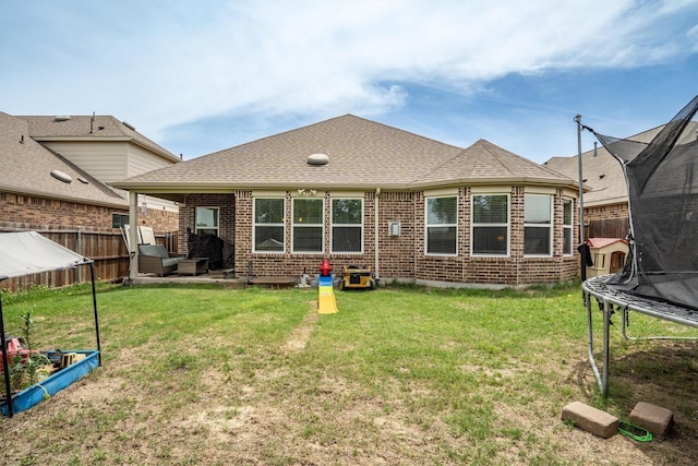 6620 Roaring Crk, Denton, TX 76226 - back of property with a trampoline, brick siding, a shingled roof, and an outdoor hangout area