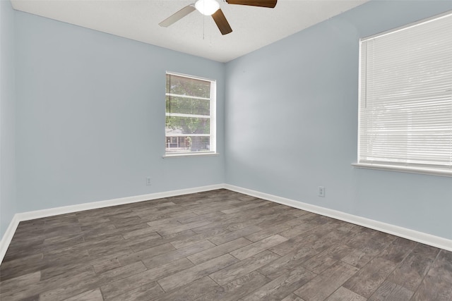 empty room with a ceiling fan, dark wood-style floors, and baseboards