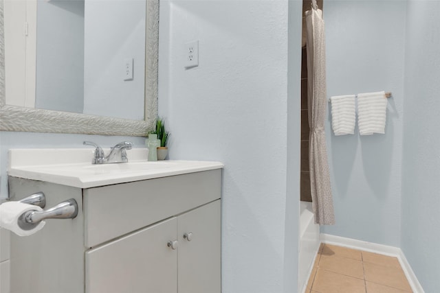 full bathroom with tile patterned flooring, vanity, baseboards, and shower / tub combo