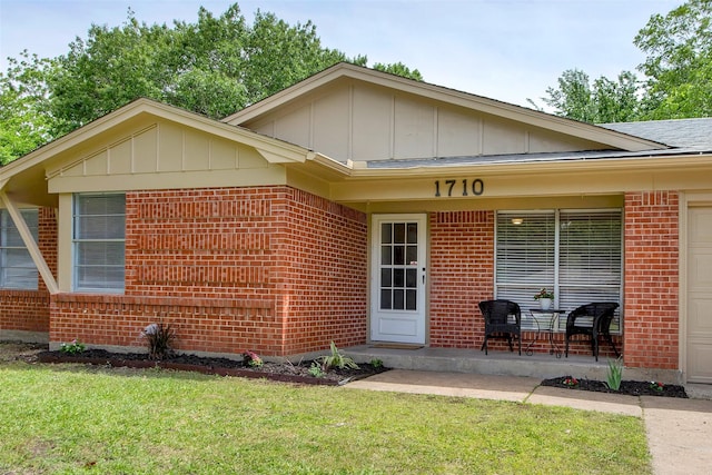 view of front of home with brick siding, a front lawn, board and batten siding, and an attached garage