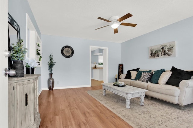 living room with a ceiling fan, light wood-style floors, and baseboards