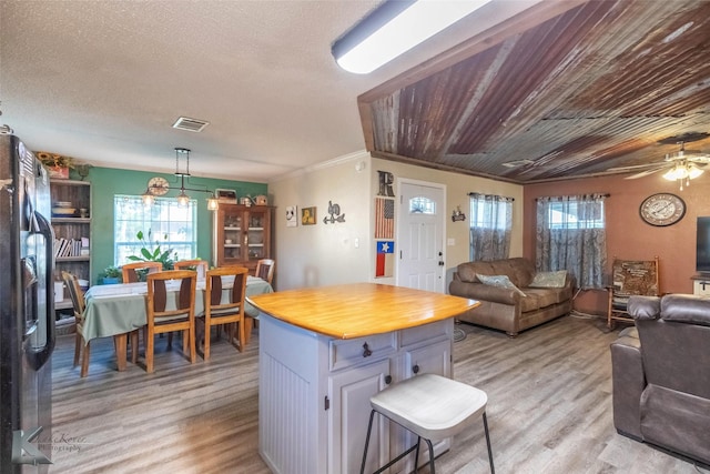 225 Field St, Clyde, TX 79510 - kitchen with light wood-style floors, black refrigerator with ice dispenser, open floor plan, wood counters, and ornamental molding