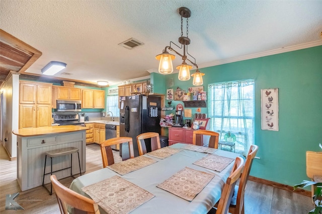 225 Field St, Clyde, TX 79510 - dining space featuring healthy amount of natural light, light wood-style floors, crown molding, a textured ceiling, and baseboards