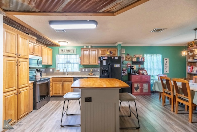 225 Field St, Clyde, TX 79510 - kitchen featuring appliances with stainless steel finishes, a sink, a kitchen bar, light wood-style flooring, and ornamental molding