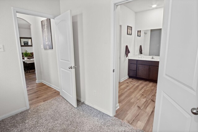 8213 Smokey Creek Pass, Fort Worth, TX 76179 - hallway with a sink, baseboards, light wood-style flooring, and light carpet