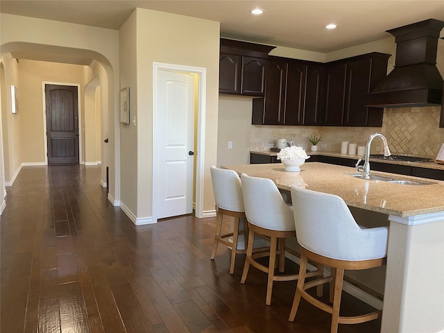 8740 Running River Ln, Fort Worth, TX 76131 - kitchen featuring custom range hood, light stone countertops, decorative backsplash, dark wood finished floors, and baseboards