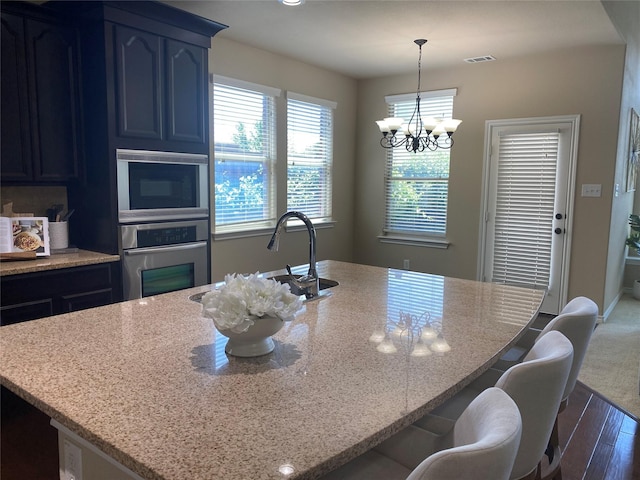 8740 Running River Ln, Fort Worth, TX 76131 - kitchen featuring appliances with stainless steel finishes, light stone counters, dark wood-type flooring, a chandelier, and a sink
