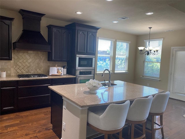 8740 Running River Ln, Fort Worth, TX 76131 - kitchen with custom range hood, stainless steel appliances, a sink, dark wood-style flooring, and an island with sink