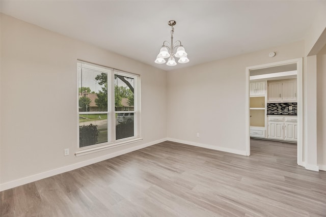 1305 Willow Way, Garland, TX 75043 - spare room featuring light wood-style flooring, a chandelier, and baseboards