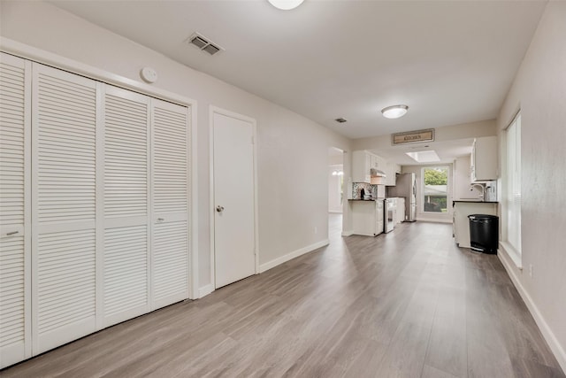 1305 Willow Way, Garland, TX 75043 - unfurnished living room featuring light wood-style floors, a sink, and baseboards