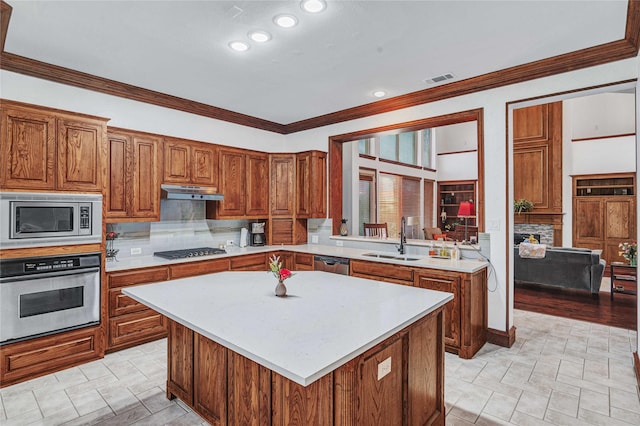 11086 Tenison Ln, Frisco, TX 75033 - kitchen with stainless steel appliances, a sink, light countertops, under cabinet range hood, and brown cabinets